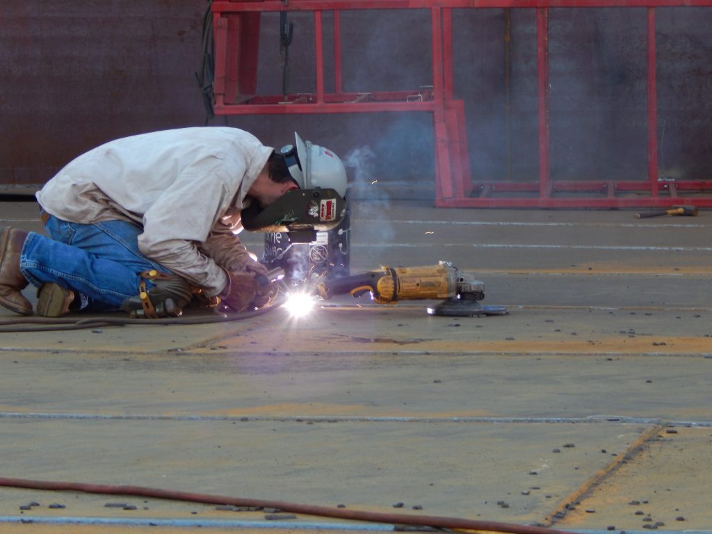 Worker welds an industrial steel tank during fabrication