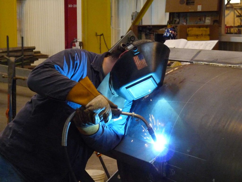 welder working on a curved sheet of metal